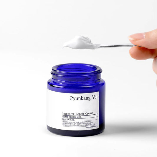Pyunkang Yul Intensive Repair Cream jar with a hand holding a spoonful of cream.