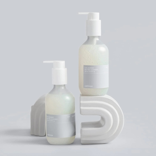 Two bottles of CELIMAX Dual Barrier Mild Gel Cleanser on a grey background with rainbow shaped platforms