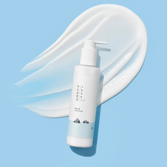 Round Lab 1025 Dokdo Cleansing Milk on a light blue background with lotion smear