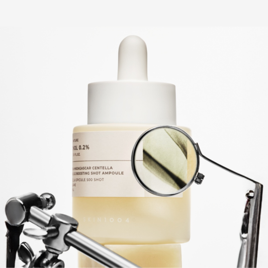 SKIN1004 Madagascar Centella Retinol 0.2 Boosting Shot Ampoule and magnifying glass on a white background