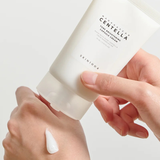 Hand dispensing SKIN1004 Madagascar Centella Tone Brightening Capsule Cream onto other hand on a white background