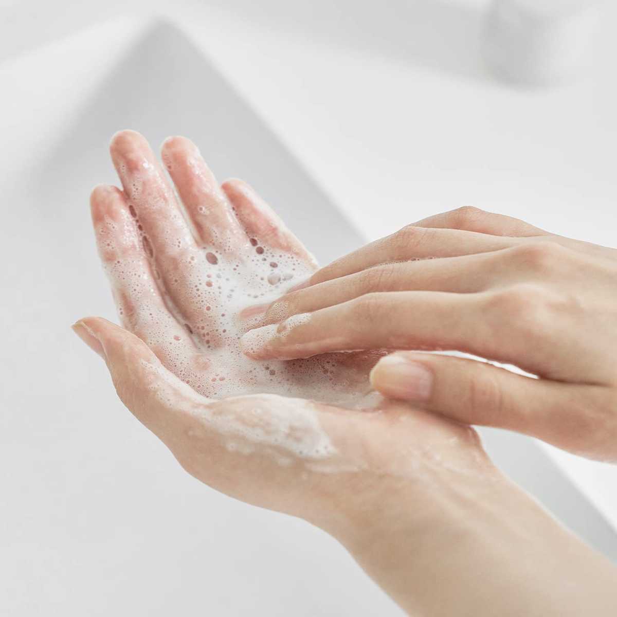 Hands rubbing the the CELIMAX Dual Barrier Mild Gel Cleanser into a rich foam