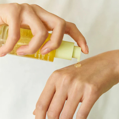 Hand  holding a bottle of Goodal Green Tangerine Vita‑C Dark Spot Care Serum and dispensing a droplet on the other hand