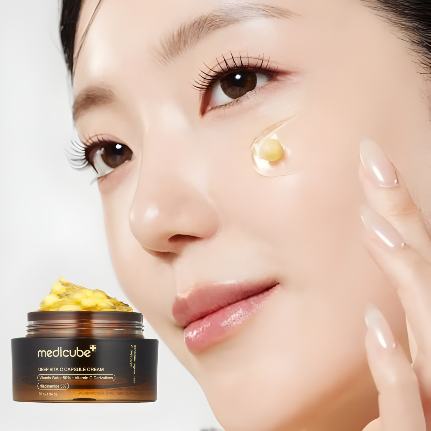 Woman applying cream to her face with a jar of Medicube Deep Vita C Capsule Cream in the foreground.