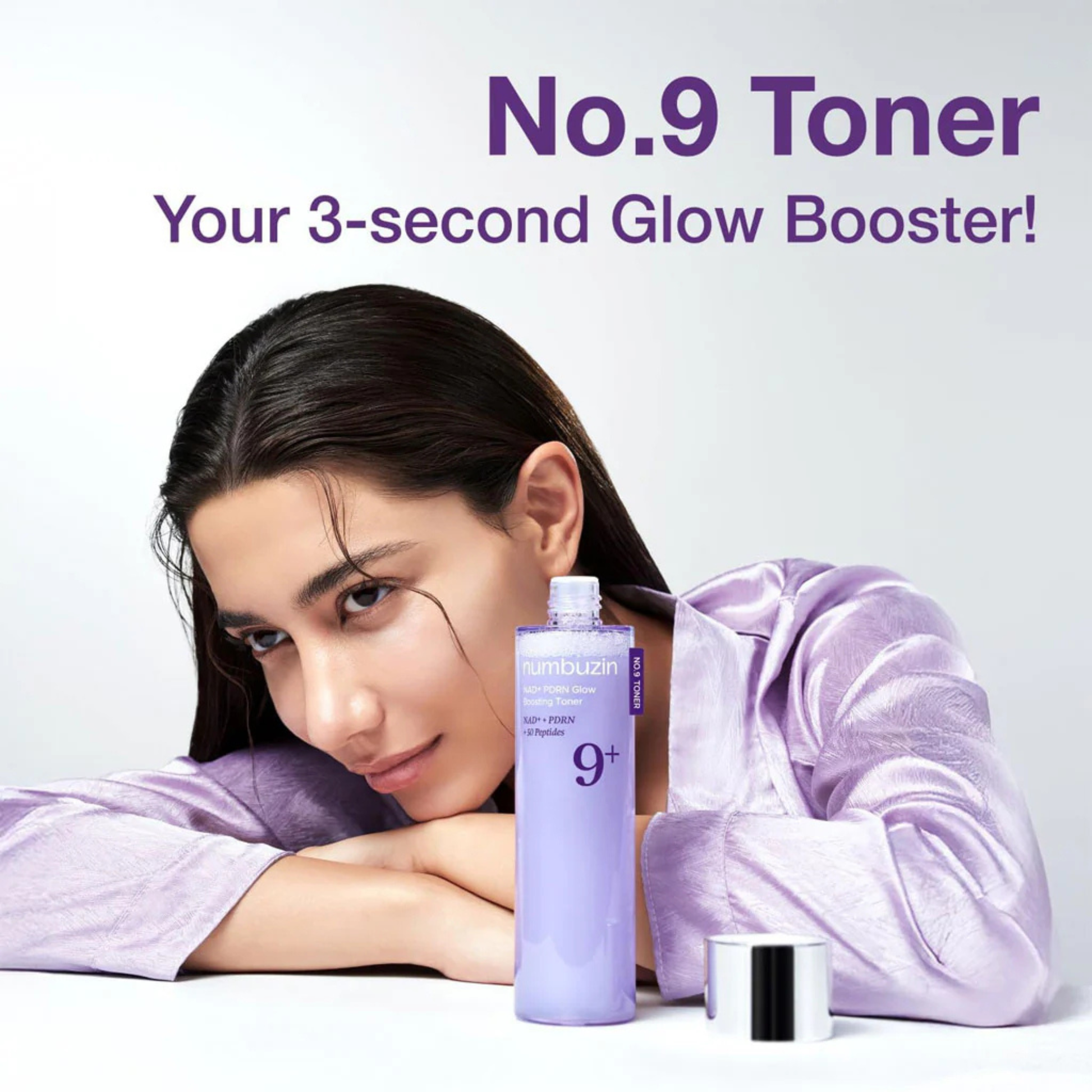 Woman resting in her hands with a bottle of Numbuzin NAD+ PDRN Glow Boosting Toner in the foreground.