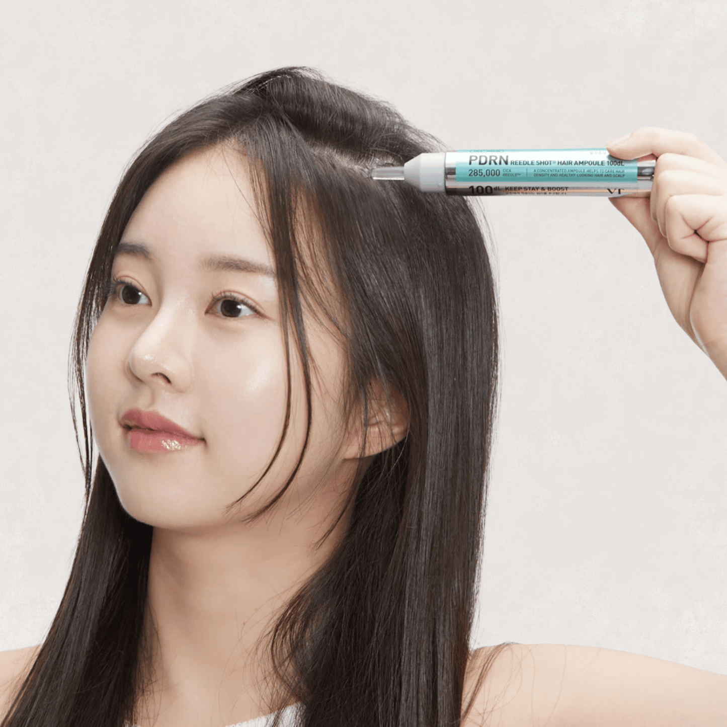 Woman with long hair holding a PDRN Reedle Shot Hair Ampoule 100dL against her head showing application
