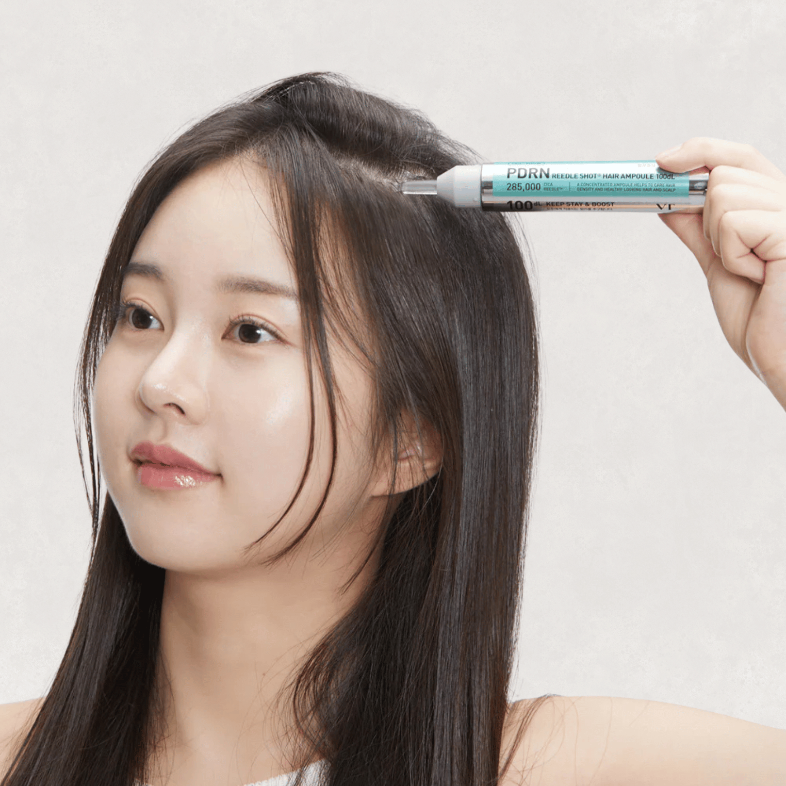 Woman with long hair holding a PDRN Reedle Shot Hair Ampoule 100dL against her head showing application