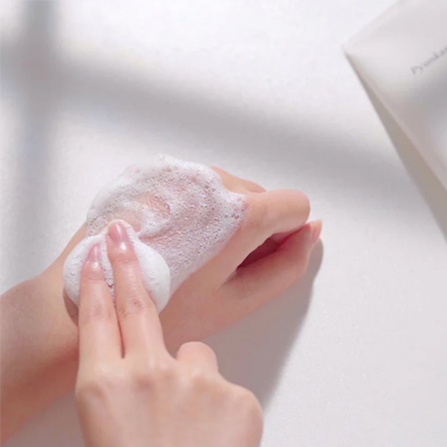 Person applying Pyunkang Yul
Cleansing Foam to hands with a blurred background
