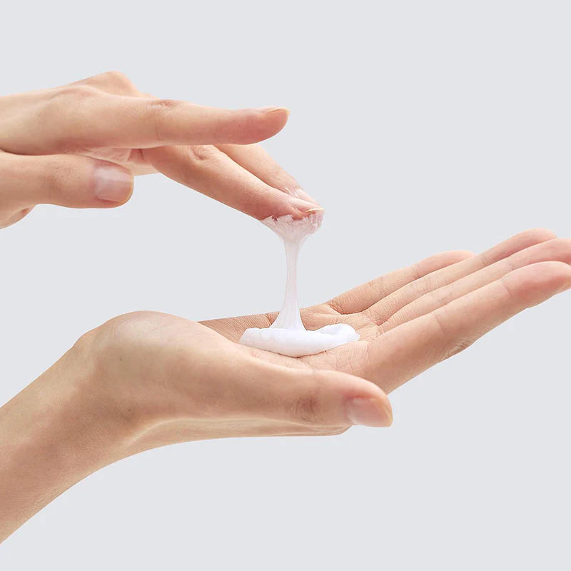 Two hands holding a small amount of Pyunkang Yul Cleansing Foam against a light gray background showing the texture of the product