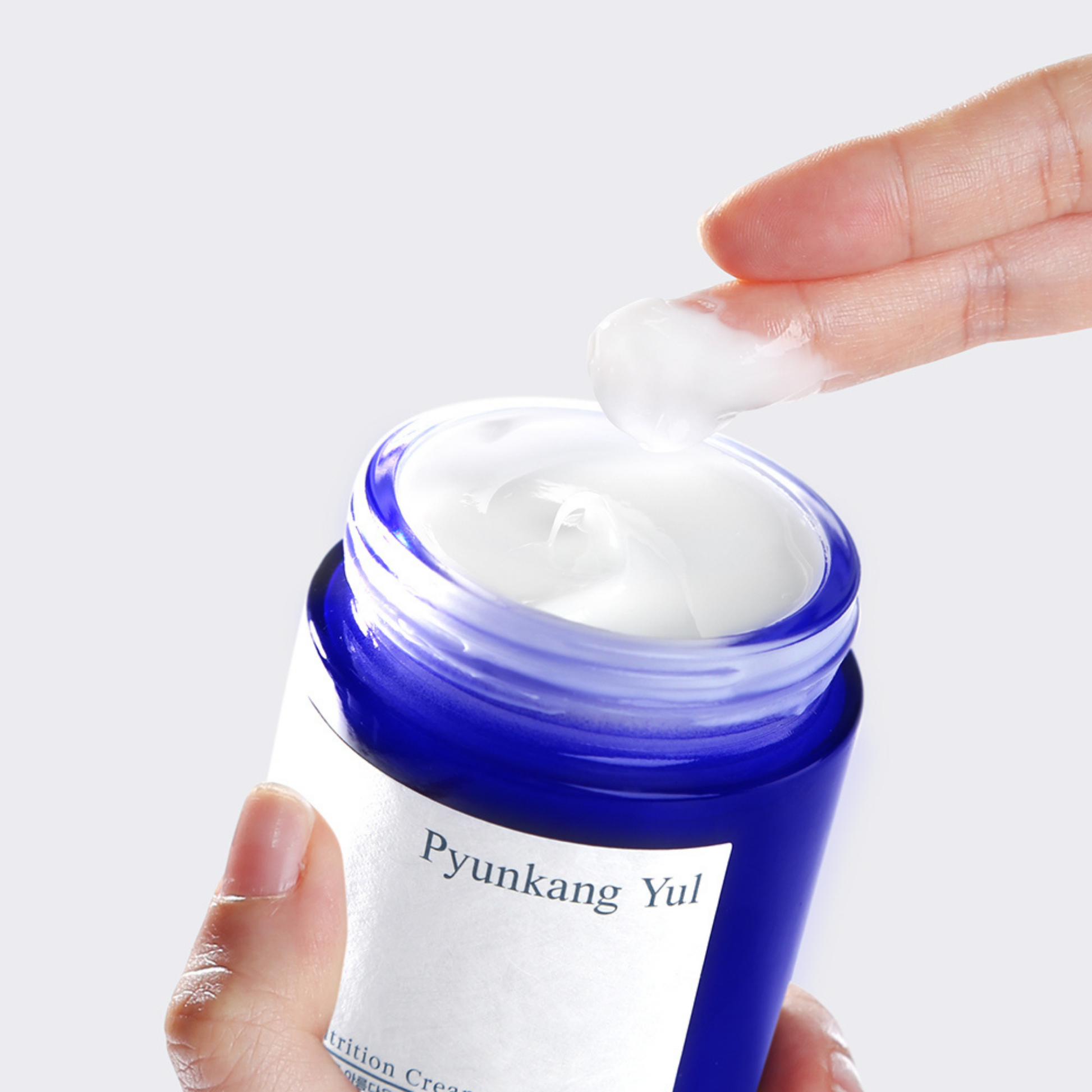 Pyunkang Yul Nutrition Cream jar with a hand applying cream on a white background
