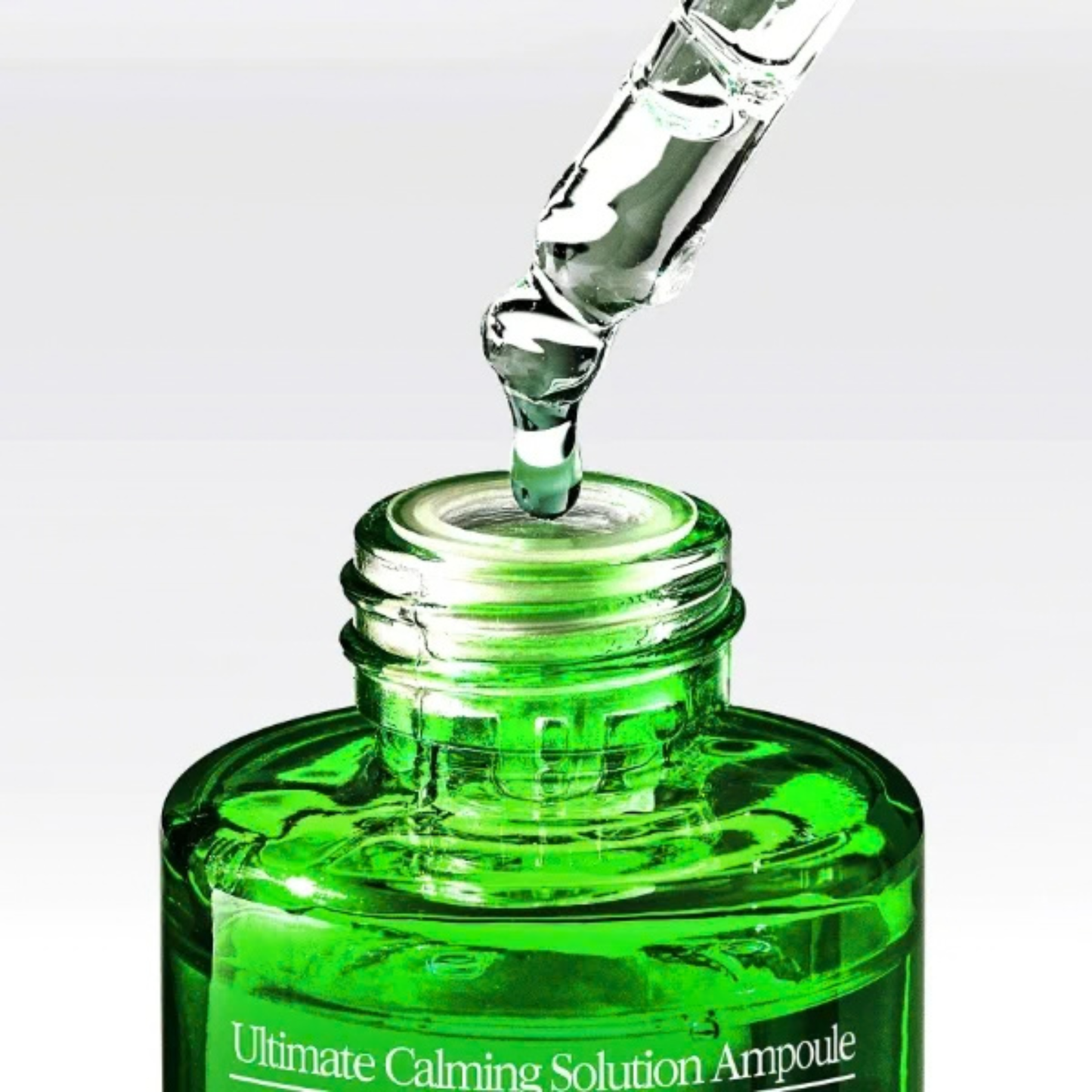 Close up of when using the Pyunkang Yul Ultimate Calming Solution Ampoule bottle with dropper and serum on a white background
