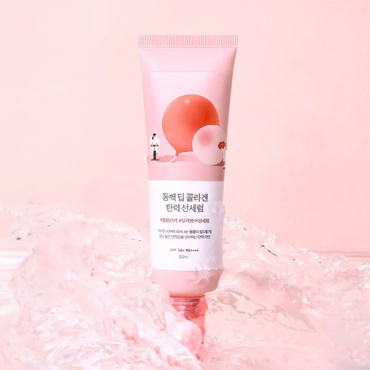 ROUND LAB Camellia Deep Collagen Firming Sun Serum splashed with water on a light pink background