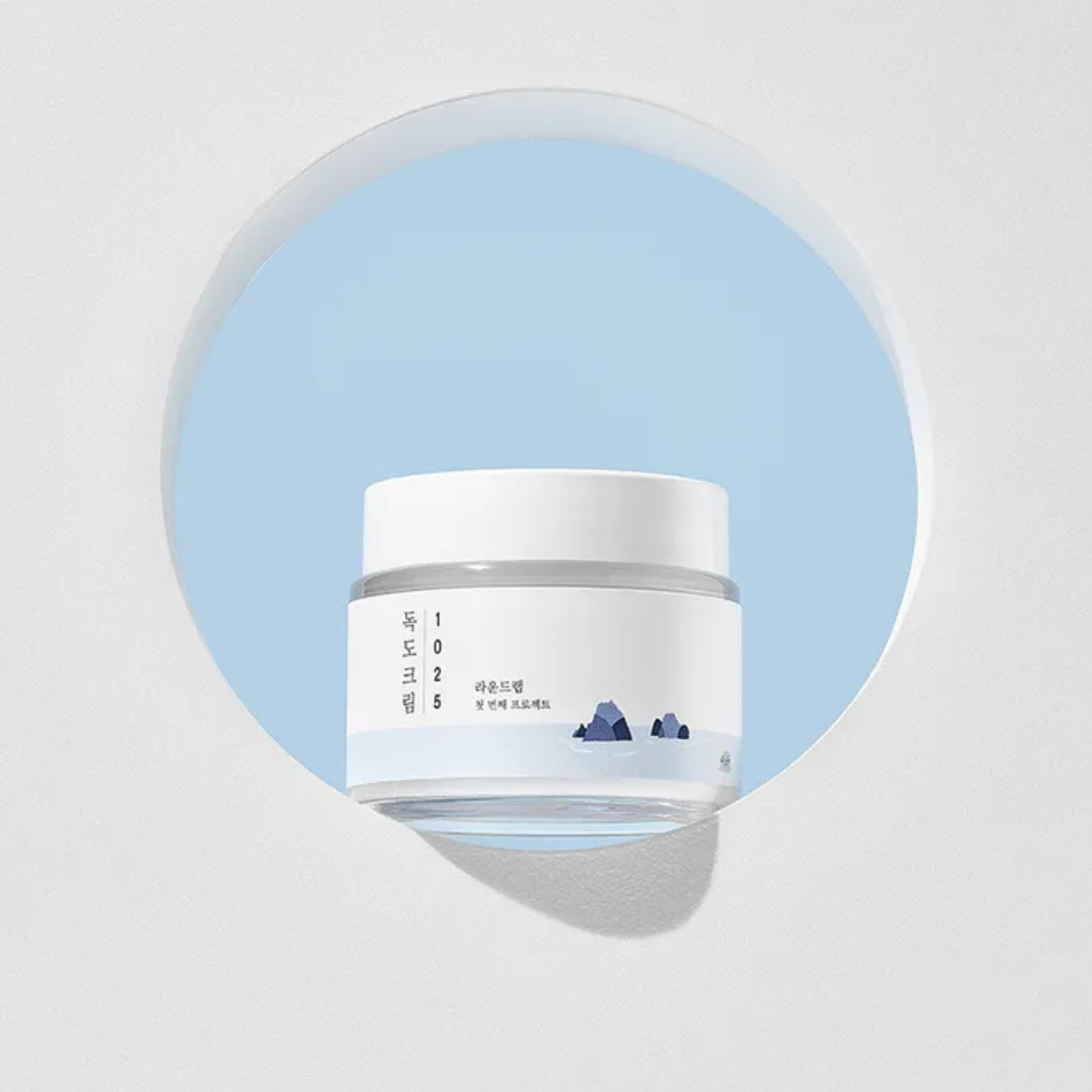 White jar of Round Lab 1025 Dokdo Cream with blue label on a light gray background