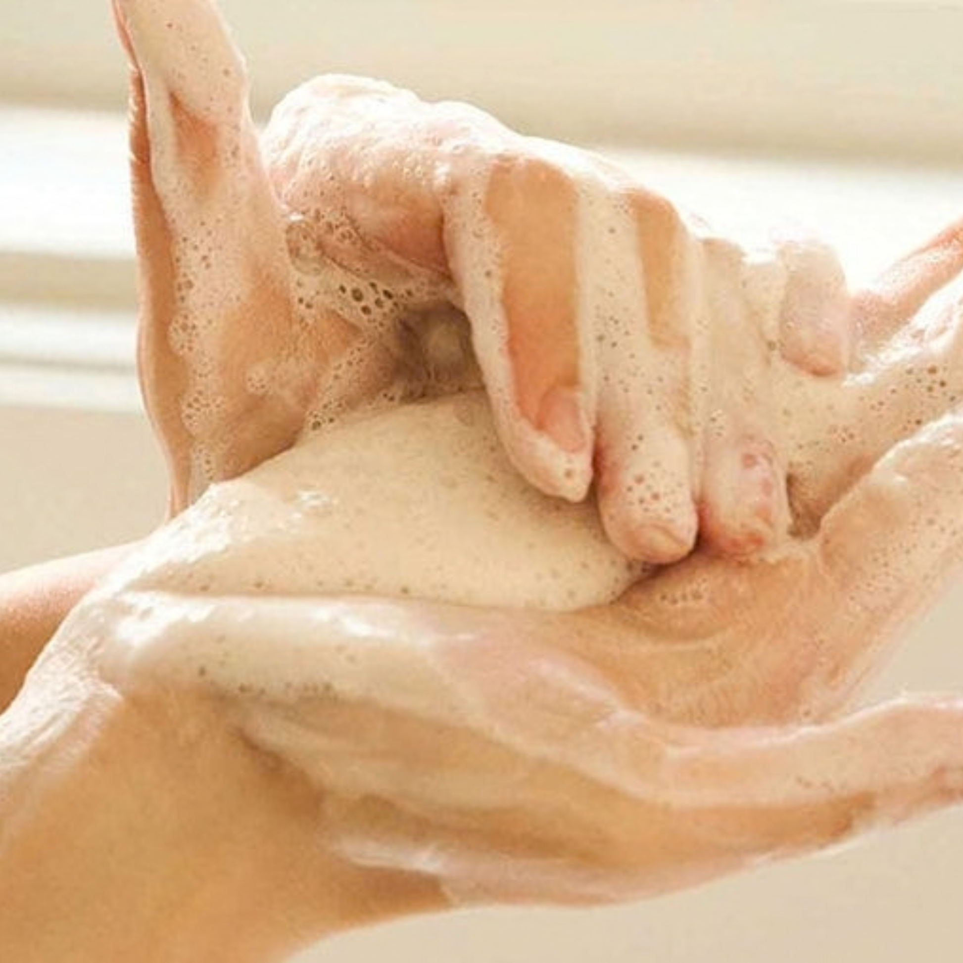 Close-up of hands showing the creamy, dense foaming of the SKIN1004 Madagascar Centella Ampoule Foam.