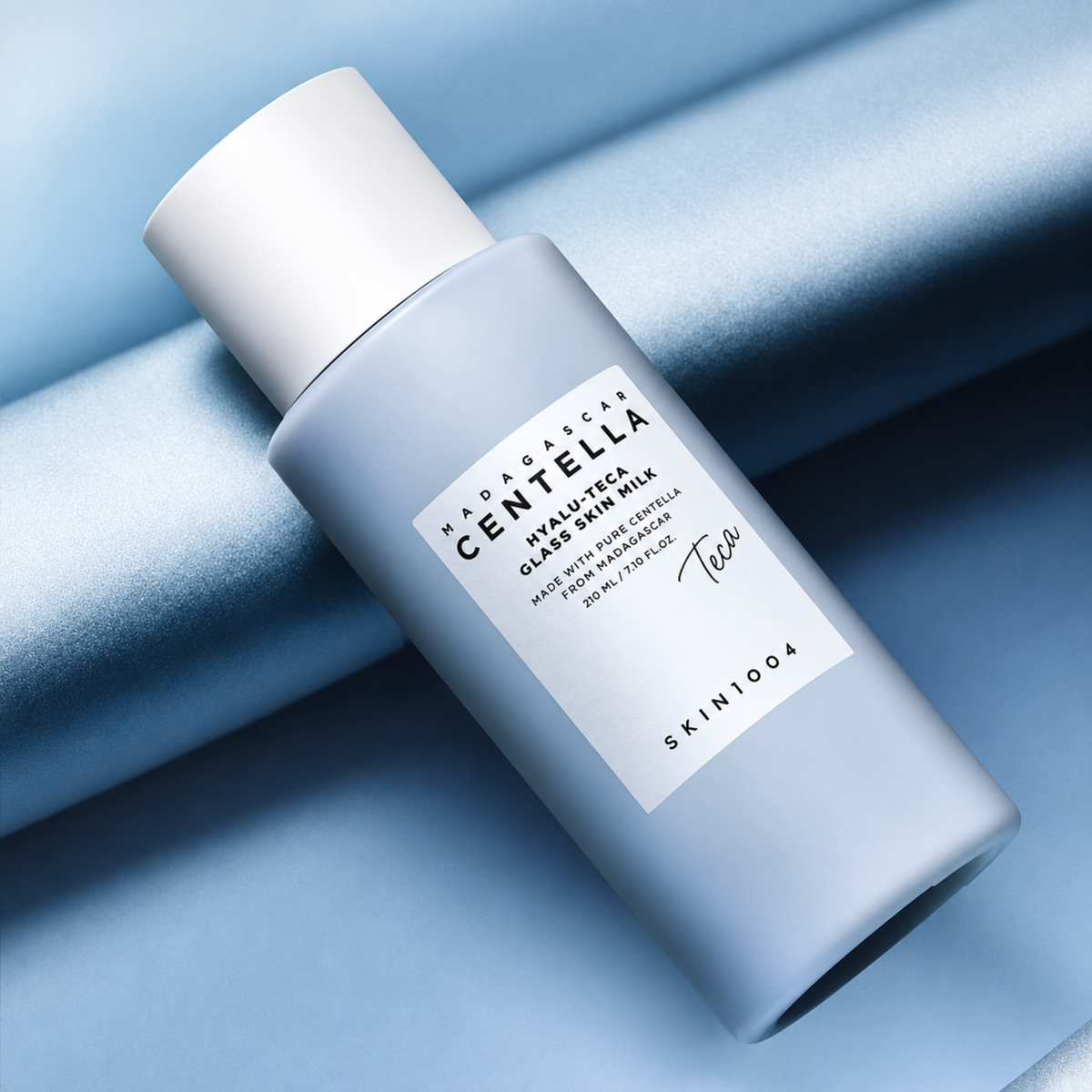 SKIN1004 Madagascar Centella Hyalu-Teca Glass Skin Milk laying against some blue material