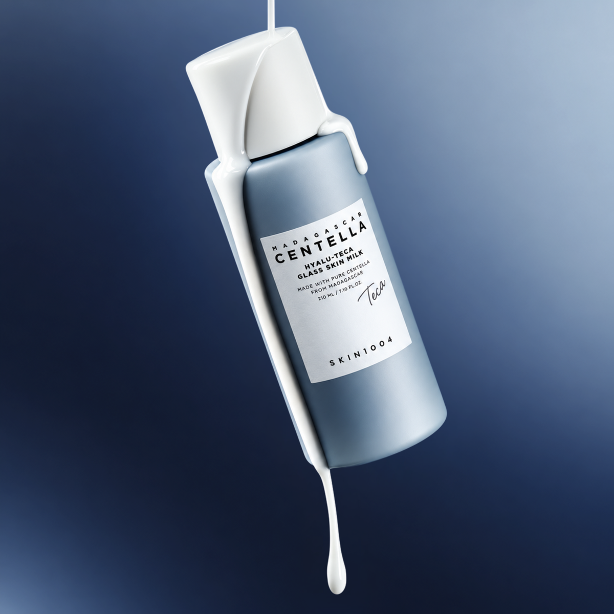 SKIN1004 Madagascar Centella Hyalu-Teca Glass Skin Milk with essence dripping from the side of the bottle on a gradient blue background