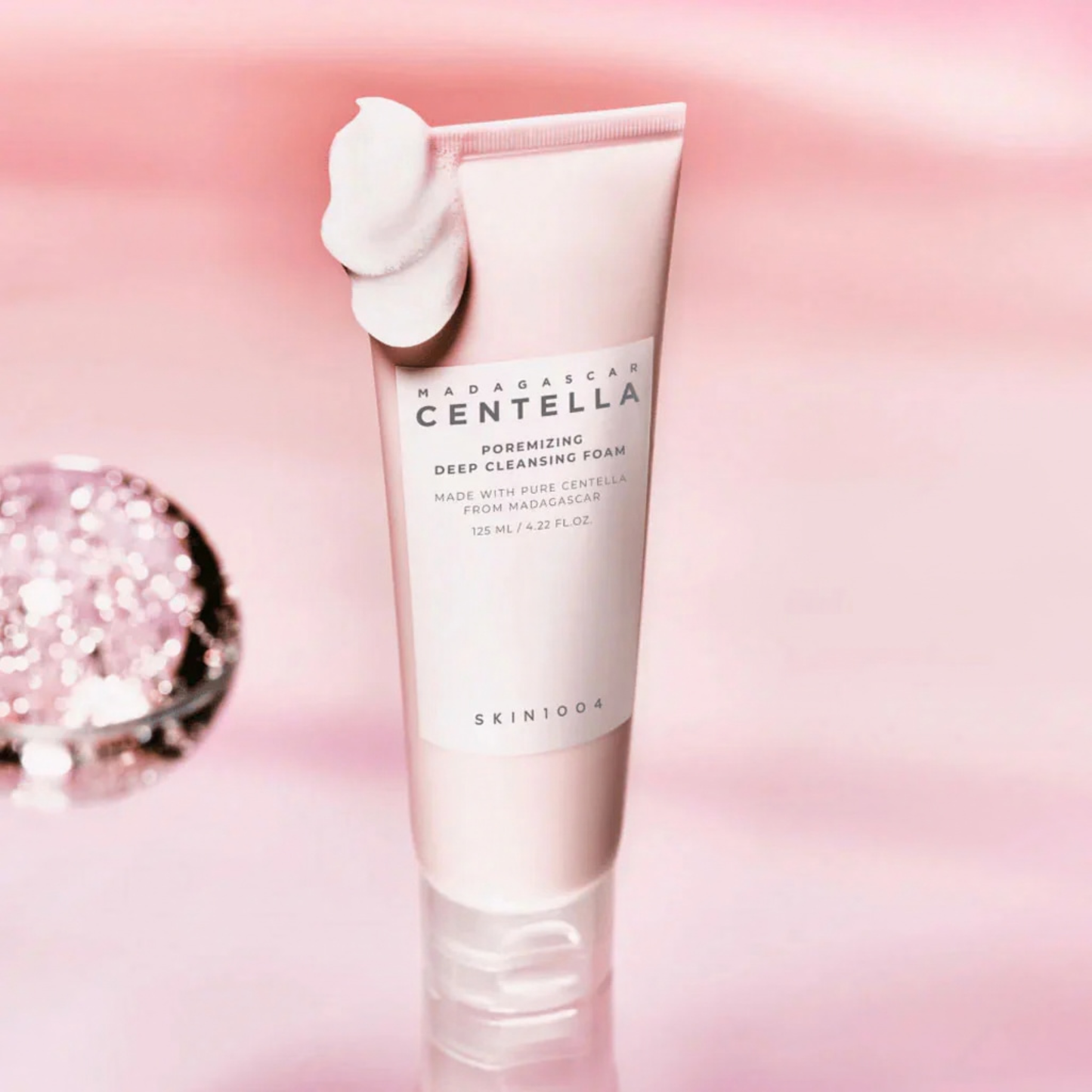 SKIN1004 Madagascar Centella Poremizing Deep Cleansing Foam with foam on the tube on a pink background