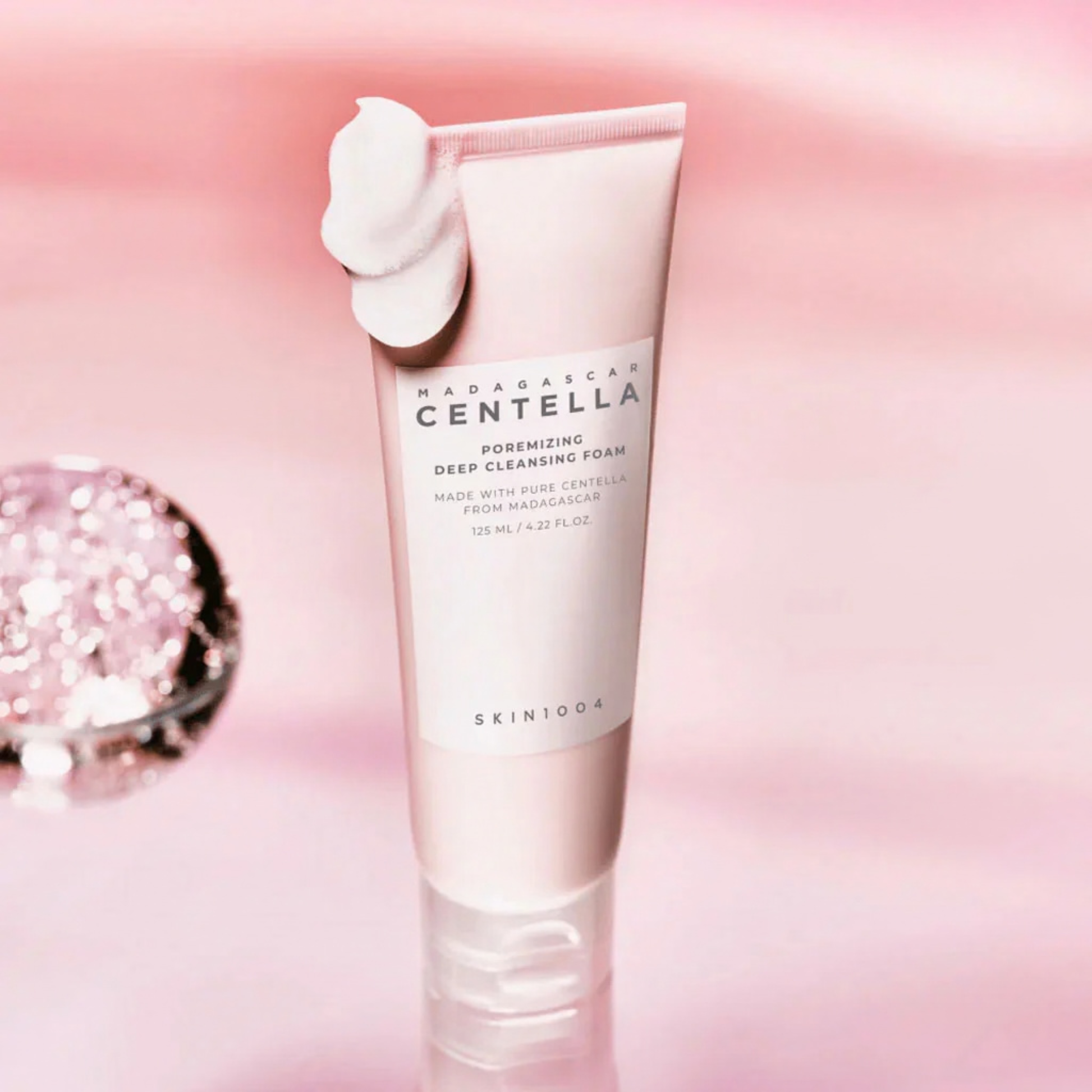 SKIN1004 Madagascar Centella Poremizing Deep Cleansing Foam with foam on the tube on a pink background