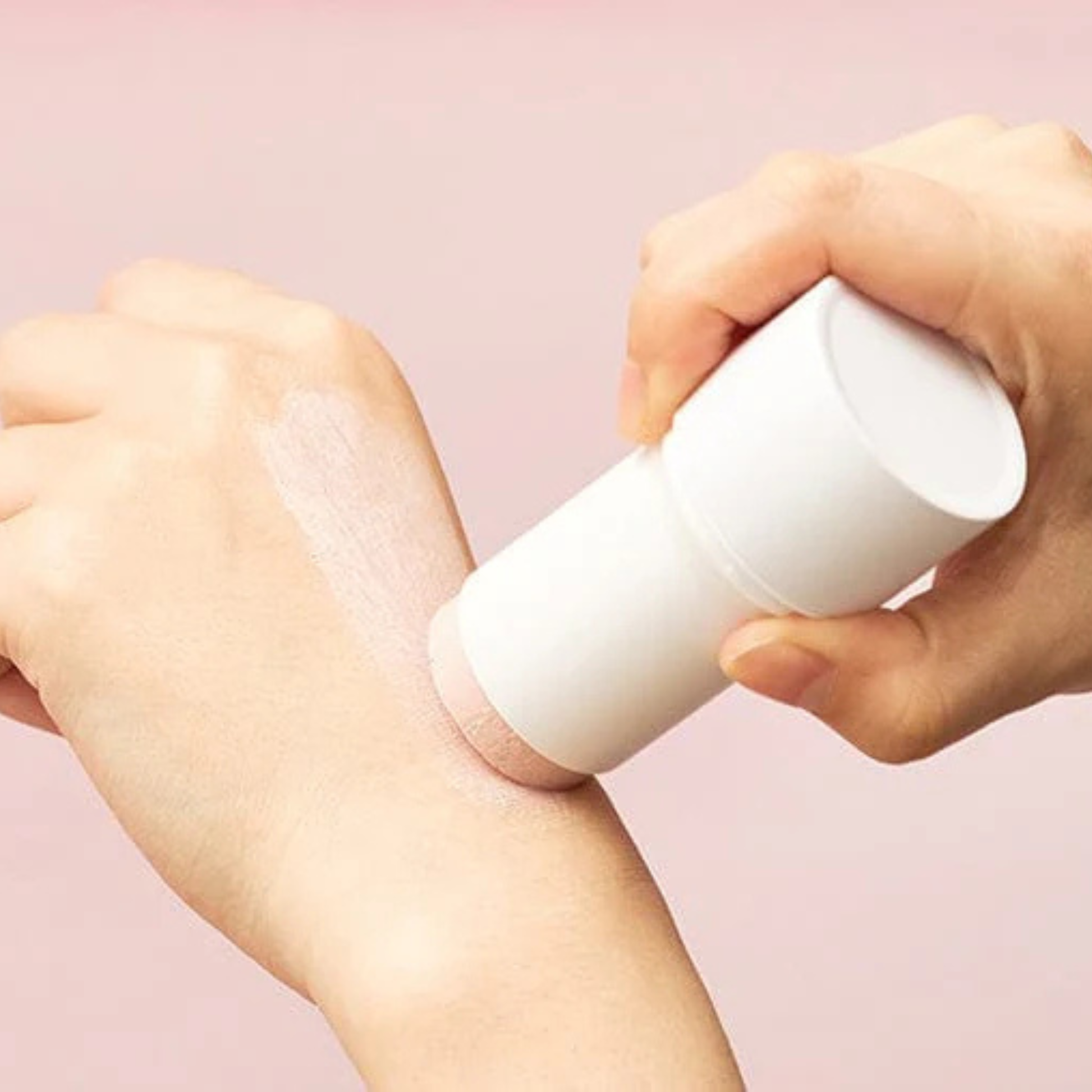Person applying SKIN1004 Madagascar Centella Poremizing Quick Clay Stick Mask to their wrist with a pink background