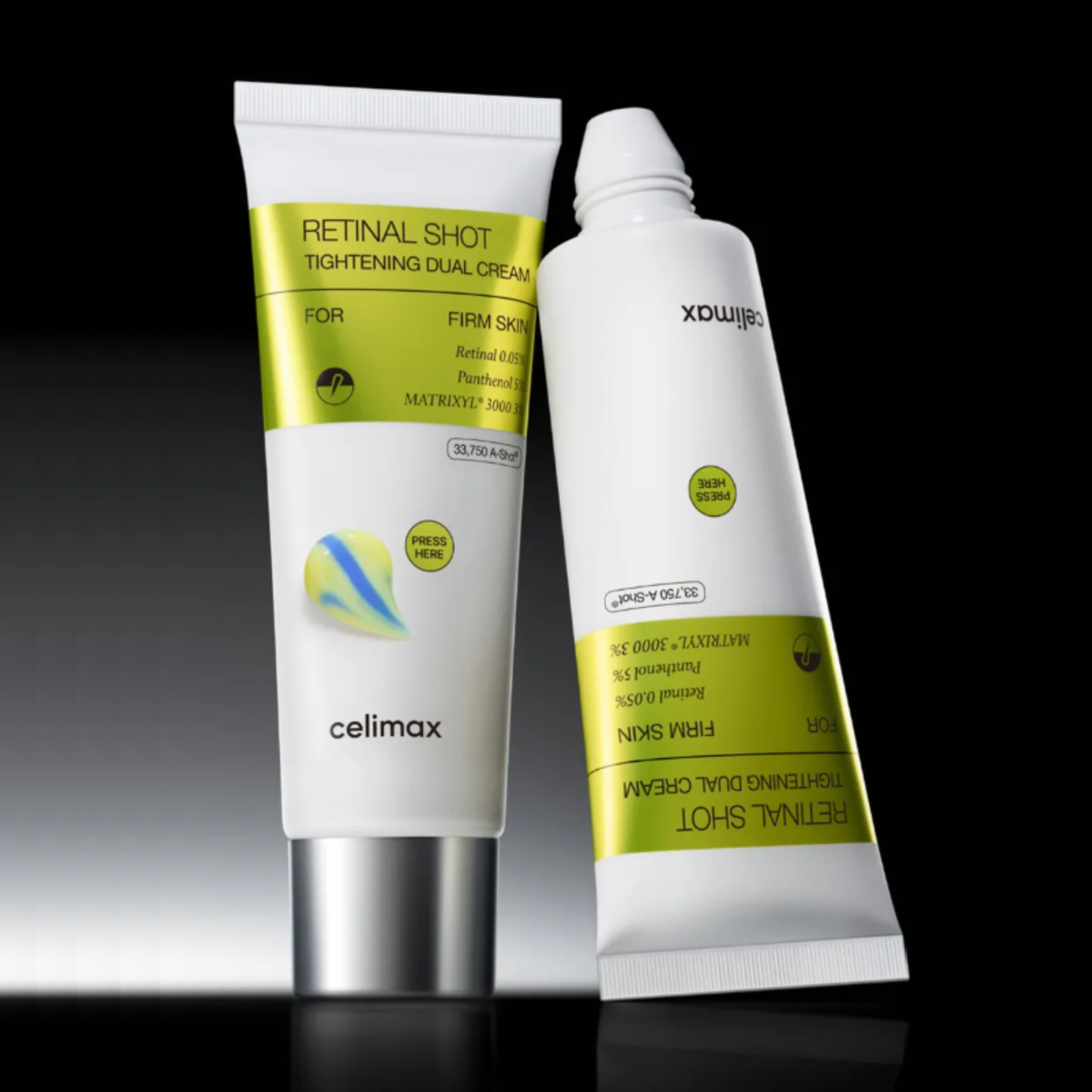 Two white cosmetic tubes of  Celimax The Vita-A Retinal Shot Tightening Dual Cream with lime green labels, displayed on a reflective black surface against a dark background.