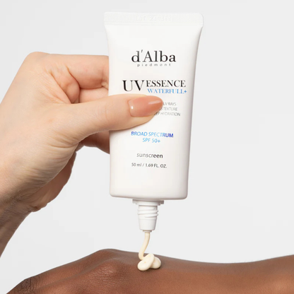 Hand applying d'Alba UV Essence Waterfull SPF 50+ PA++++ Sun Cream to skin with a white background