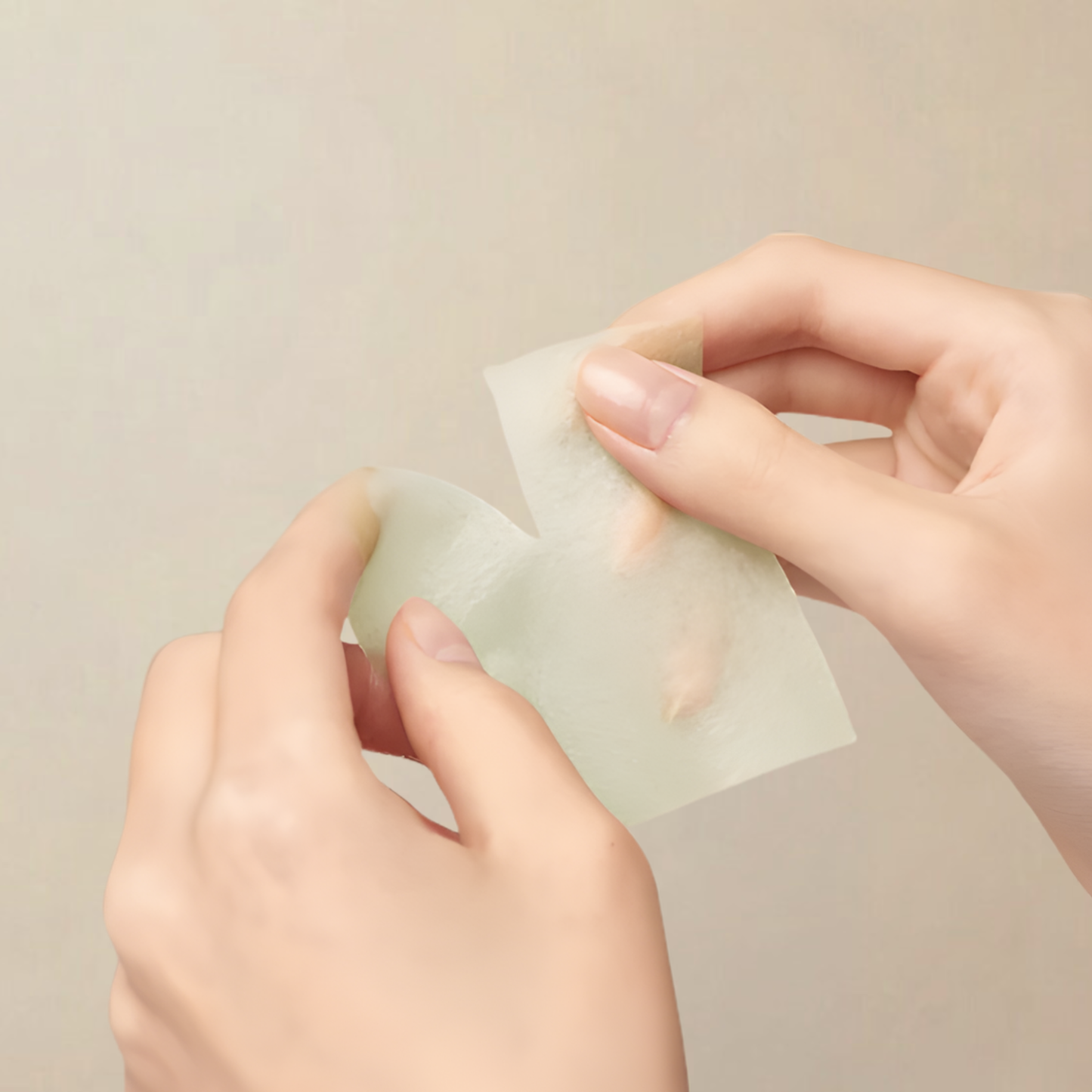 Hands holding a molvany Artichoke Soothing Acne Pore Toner Pad showing how the pads can be torn apart on a beige background